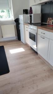 a kitchen with white appliances and a wooden floor at Auf dem Land in Wittbek