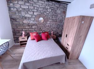a bedroom with a bed with red pillows and a brick wall at OLOO Habitat - Le 3 in Lure