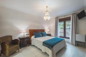 a bedroom with a bed and a chair and a television at Hotel Amapola La Barrosa in Novo Sancti Petri