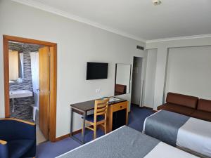 a hotel room with a desk and a bed and a bed and a deskicter at Hotel Feira Pedra Bela in Santa Maria Da Feira