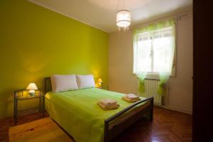a green bedroom with a bed with two towels on it at Apartman Adria in Poreč