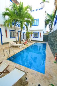 a pool with palm trees in front of a house at Bayahibe Essentials Rooms in Bayahibe