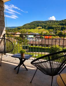 a table and chairs on a balcony with a view at Appart Vosges in Fresse-sur-Moselle
