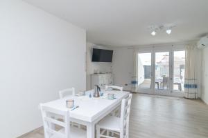 a white dining room with a white table and chairs at Bilocale nuovo Budoni centro in Budoni