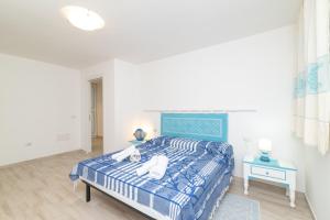 a bedroom with a bed with a blue and white comforter at Bilocale nuovo Budoni centro in Budoni