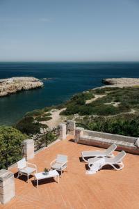 a group of chairs and lounge chairs on a patio overlooking the ocean at Villa Incina - Sea House in Polignano a Mare