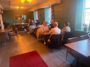 a group of people sitting at tables in a restaurant at Charlottenlunds Gårdshotell & Restaurang in Långaryd