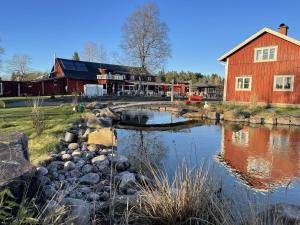 a barn and a pond in front of a building at Charlottenlunds Gårdshotell & Restaurang in Långaryd