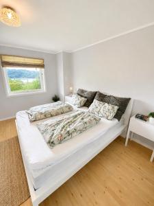 a white bed in a white room with a window at Jåsund SunView in Lyngdal