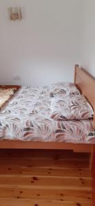 an unmade bed in a room with a wooden floor at Sušica Apartman in Kovačka Dolina