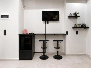 a bar with two stools and a tv on a wall at ILoveHome Mini in Kalamata