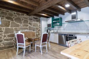 a kitchen with a table and chairs and a stone wall at Casa do Capitan cdc in Leiro