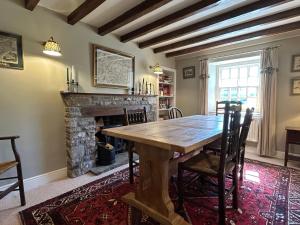 a dining room with a wooden table and a fireplace at Tarn House in Hawes