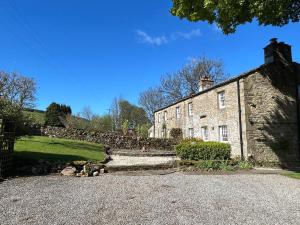 an old stone house with a stone wall and a driveway at Tarn House in Hawes
