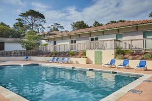 a swimming pool with lounge chairs and a house at Résidence Odalys Bleu Ocean in Moliets-et-Maa