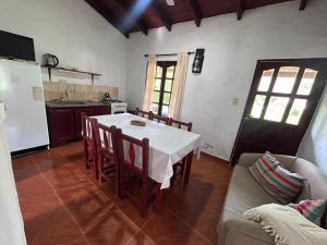 a kitchen with a white table and chairs and a refrigerator at El Paso Ibera Cabañas in Colonia Carlos Pellegrini