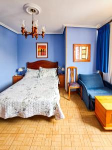 a bedroom with blue walls and a bed and a chair at Hotel Imperial in Tazones