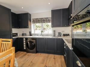 a kitchen with black cabinets and a dishwasher at Brook Cottage in Coleraine