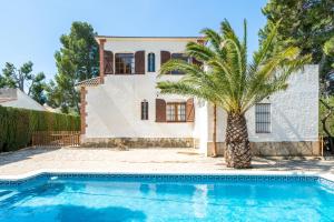 a house with a palm tree in front of a swimming pool at Hauzify I Casa Cardona in Les tres Cales