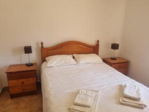 a bedroom with a bed with two nightstands and two lamps at CCCA Monte Loureiro in Raposeira +10 photos