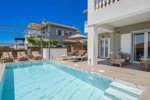 a swimming pool with chairs and a house at Villa Mary in Kefallonia