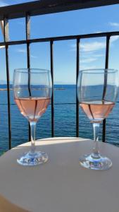two glasses of wine sitting on a table near the water at To Nisaki in Loutraki