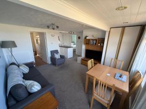 a living room with a couch and a table at 92 Blueberry Lodge - Sea Views in Westward Ho +10 photos