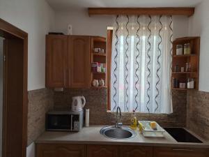 a kitchen with a sink and a microwave and a window at Apartmani Sorić in Prijeboj +2 photos