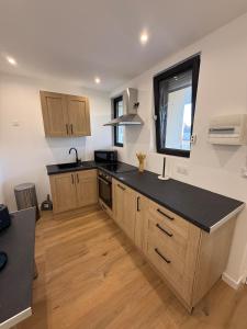 a kitchen with wooden cabinets and a black counter top at Cocon de Montluçon in Montluçon +17 photos