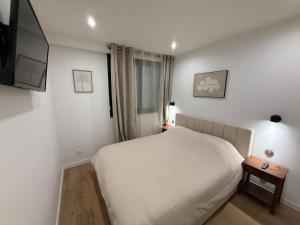 a bedroom with a white bed and a side table at Cocon de Montluçon in Montluçon