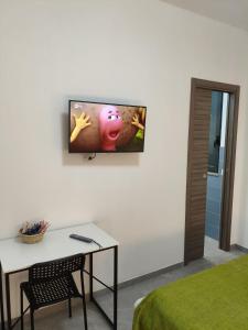 a room with a tv on a wall with a table at Affittacamere Domus Roseto in Roseto Capo Spulico