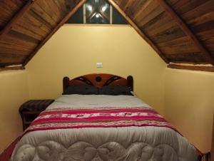a bed in a room with a wooden ceiling at Pablito Hostel Challhuay in Colcapampa