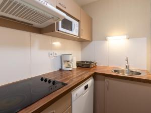 a small kitchen with a sink and a microwave at Les Chalets d Ax N212 - 2P6C in Ax-les-Thermes