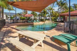 a picnic table and chairs next to a swimming pool at Jacaranda Holiday Park in North Haven