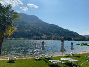 a group of chairs and umbrellas on the shore of a lake at B&B K Beach Lake Endine in Endine Gaiano