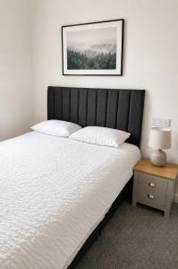 a bed with a black headboard next to a table at Snowdon Apartments in Stirling