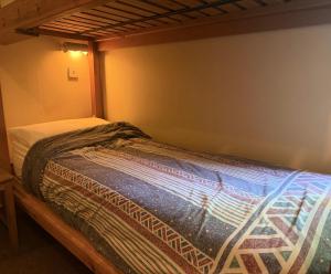 a small bed in a bedroom with a bedspread on it at Newtonmore Hostel in Newtonmore