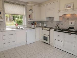 a white kitchen with white cabinets and a window at Riverdene in Omagh
