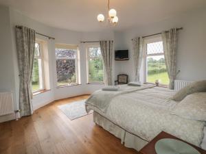 a bedroom with a large bed and windows at Riverdene in Omagh