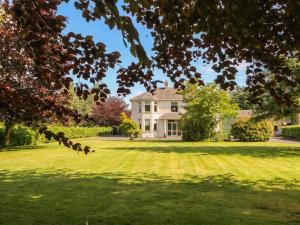 a large white house on a grassy field at Riverdene in Omagh