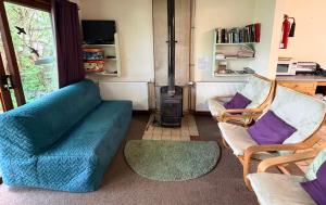 a living room with a couch and two chairs and a stove at Newtonmore Hostel in Newtonmore +7 photos