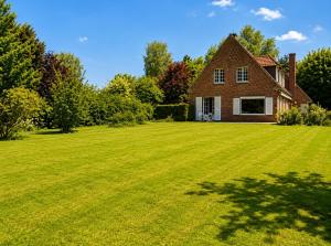 a large grassy yard with a brick house at Les jardins de Beaumont in Hem