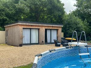 a swimming pool in front of a tiny house at Longovers Lodge in Westbourne