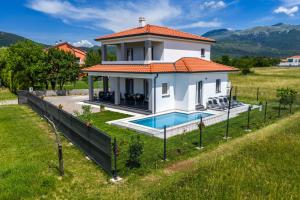 a white house with a swimming pool in a field at Vila Gaspar in Dražice