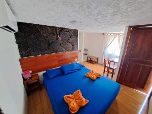 a bedroom with a blue bed with orange bows on it at HOSTAL TERO REAL in Puerto Villamil