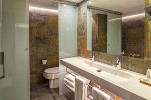 a bathroom with a sink and a toilet and a mirror at Hotel Gran Derby Suites, a Small Luxury Hotel of the World in Barcelona +37 photos