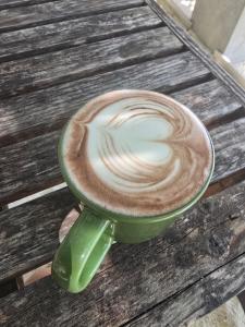 a green cup of coffee sitting on a wooden table at Dhiffushi Reef & Beach in Dhiffushi