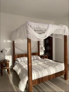 a bedroom with a canopy bed with white sheets at Villa in Vipingo in Vipingo +20 photos