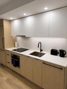 a kitchen with white cabinets and a sink at Modern suite in Surrey