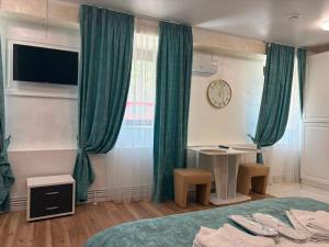 a bedroom with green curtains and a table and a clock at Grey Boutique Hotel Palas in Iaşi